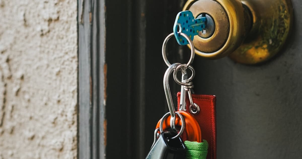 Trousseau de plusieurs cles colorees suspendu a une poignee de porte, illustrant le partage des cles en colocation
