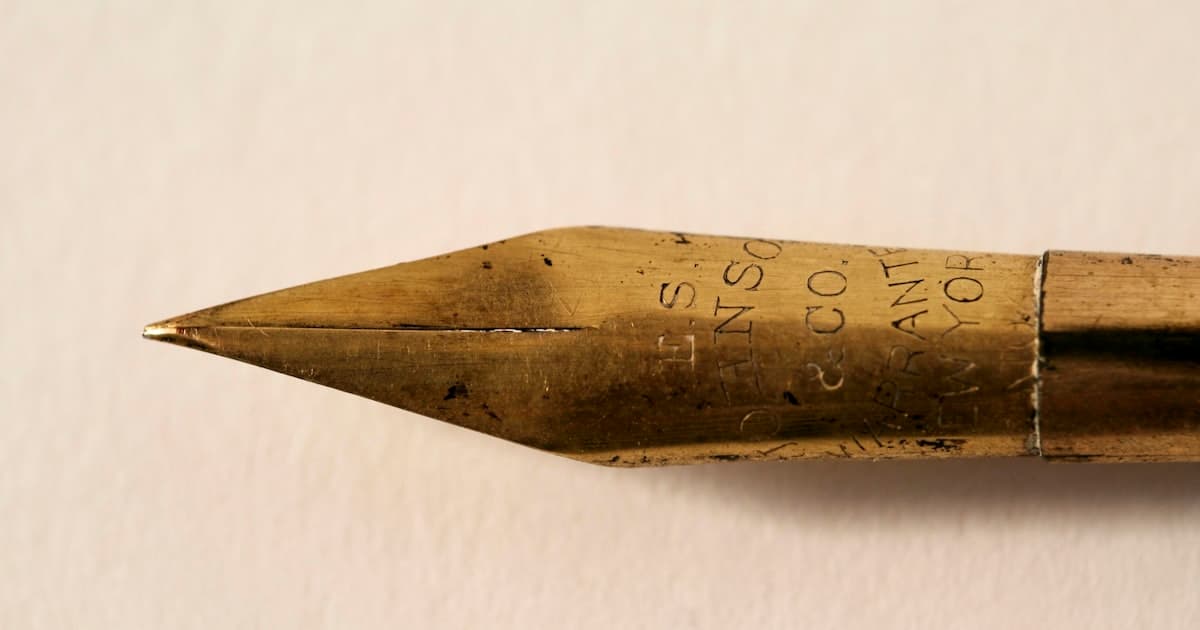 Gros plan macro sur la pointe doree d'un stylo plume ancien, illustrant la signature d'un bail notarie