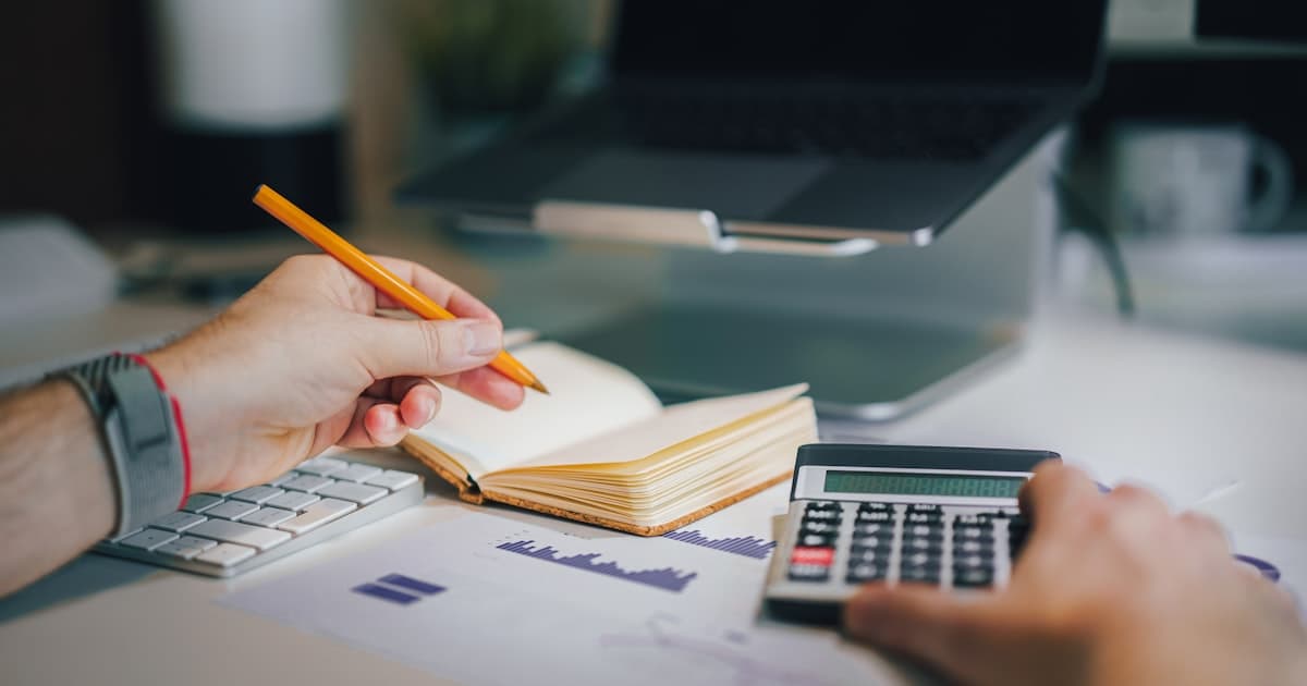 Mains calculant un budget de formation avec une calculatrice et un carnet de notes, illustrant les dispositifs de financement AGEFICE et OPCO EP