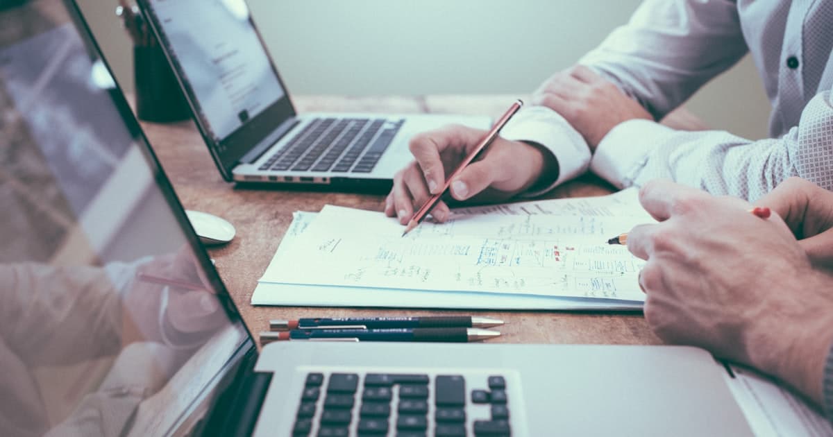 Deux personnes planifiant une strategie de prospection avec ordinateurs et notes sur une table